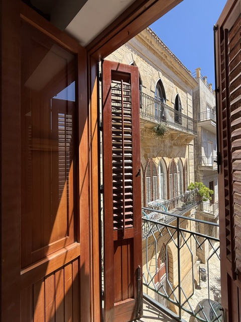 Balcony doors open onto a stone street in the old town
