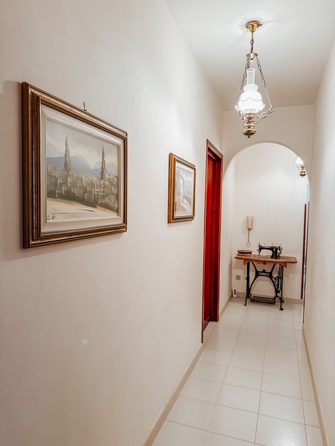 Arched hallway with framed paintings and antique sewing table