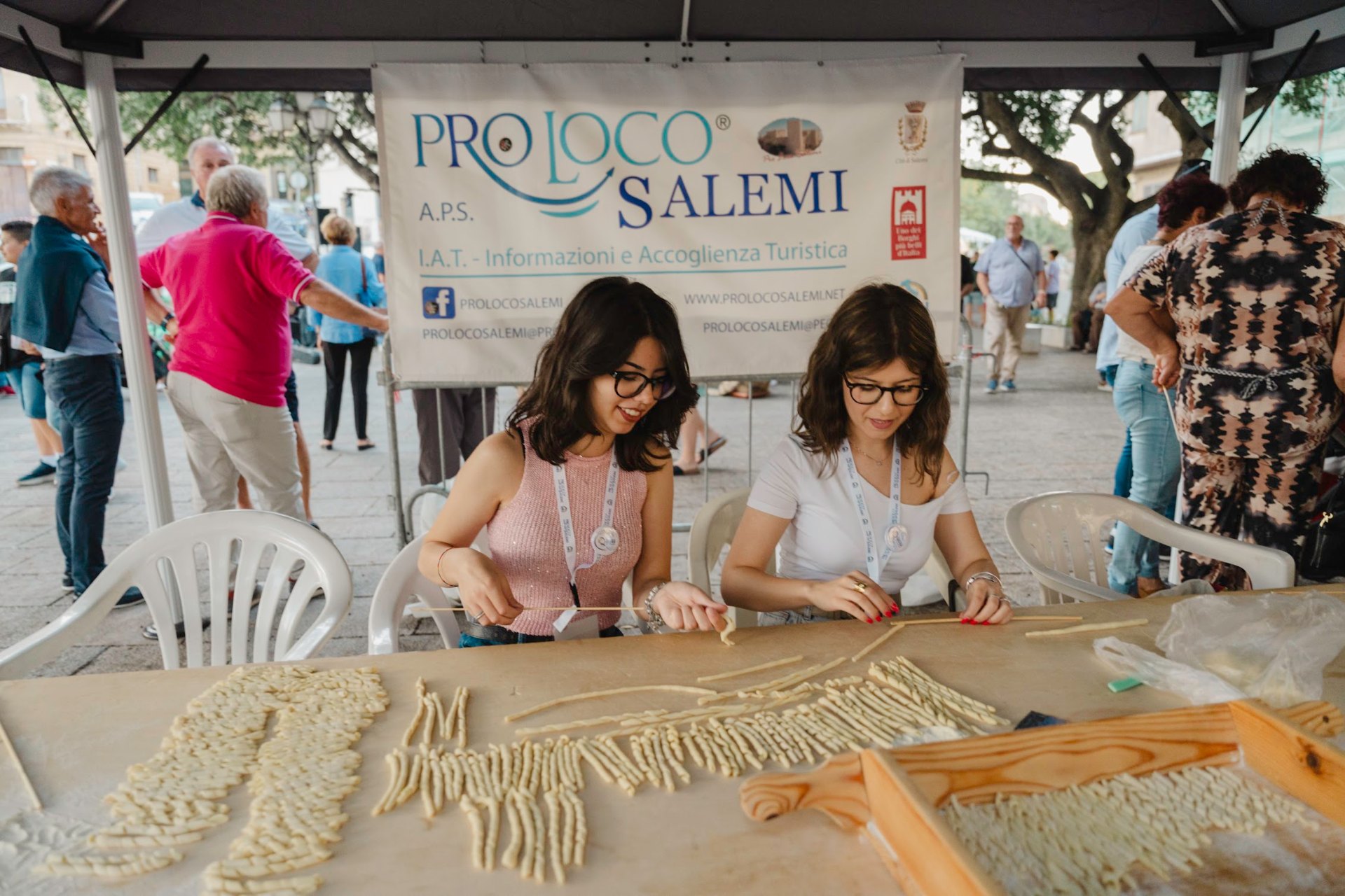 Women rolling fresh busiata pasta by hand at the Pro Loco Salemi stand during the Busiata Festival