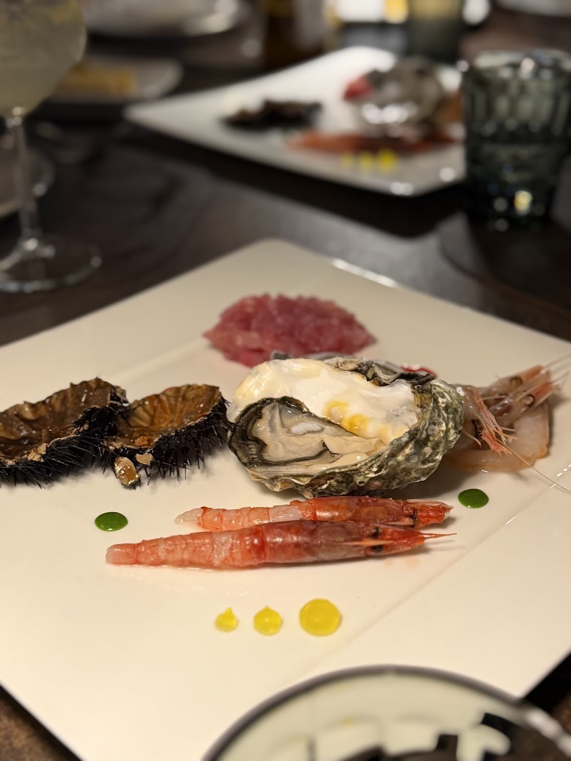 Raw Sicilian seafood plate with oyster, red prawns, sea urchin and tuna tartare